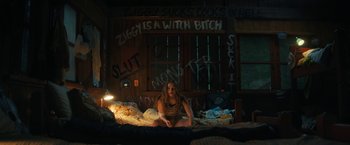 Movie still from “Fear Street: Part Two - 1978” (2021), directed by Leigh Janiak – A woman sitting on a bed in front of a wall; Wide shot, High angle