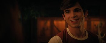 Movie still from “Fear Street: Part Two - 1978” (2021), directed by Leigh Janiak – A young man smiling for the camera in the dark; Close Up shot, Over the shoulder angle