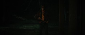 Movie still from “Fear Street: Part Two - 1978” (2021), directed by Leigh Janiak – A man holding an axe standing in the middle of a dark forest; Medium shot, Over the shoulder angle
