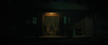 Movie still from “Fear Street: Part Two - 1978” (2021), directed by Leigh Janiak – A person sitting in a chair in front of a building; Extreme Wide shot, Over the shoulder angle