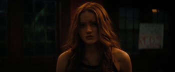 Movie still from “Fear Street: Part Two - 1978” (2021), directed by Leigh Janiak – A woman with long red hair is looking at the camera; Close Up shot, Low angle