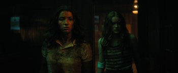 Movie still from “Fear Street: Part Two - 1978” (2021), directed by Leigh Janiak – Two women standing next to each other in a dark room; Medium shot, Low angle