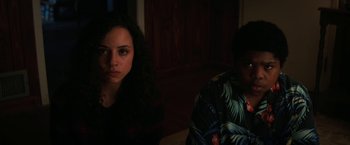 Movie still from “Fear Street: Part Two - 1978” (2021), directed by Leigh Janiak – A woman and a man sitting next to each other in a dark room; Close Up shot, High angle