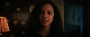 Movie still from “Fear Street: Part Two - 1978” (2021), directed by Leigh Janiak – A woman with long curly black hair wearing a black t - shirt; Close Up shot, Over the shoulder angle