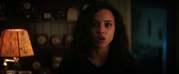 Movie still from “Fear Street: Part Two - 1978” (2021), directed by Leigh Janiak – A woman with long curly black hair stares into the camera; Close Up shot, Over the shoulder angle