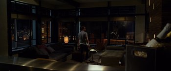 Movie still from “Friends with Benefits” (2011), directed by Will Gluck – A man standing in a living room next to a window; Wide shot, High angle