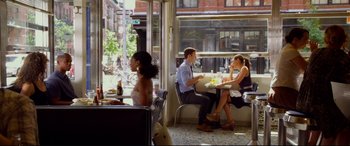 Movie still from “Friends with Benefits” (2011), directed by Will Gluck – A man and a woman sitting at a table in front of a window; Wide shot, Over the shoulder angle