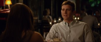 Movie still from “Friends with Benefits” (2011), directed by Will Gluck – A man sitting at a table with a glass of wine; Medium shot, Over the shoulder angle