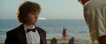 Movie still from “Friends with Benefits” (2011), directed by Will Gluck – A boy in a suit and bow tie standing in front of the ocean; Close Up shot, Over the shoulder angle