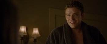 Movie still from “Friends with Benefits” (2011), directed by Will Gluck – A man in a robe smiling for the camera in front of a lamp; Close Up shot, Over the shoulder angle