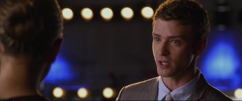 Movie still from “Friends with Benefits” (2011), directed by Will Gluck – A man wearing a suit and tie standing in front of lights; Close Up shot, Over the shoulder angle