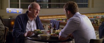 Movie still from “Friends with Benefits” (2011), directed by Will Gluck – Two people sitting at a table with plates of food; Medium shot, Over the shoulder angle