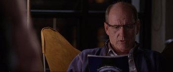 Movie still from “Friends with Benefits” (2011), directed by Will Gluck – An older man sitting in a chair reading a book; Close Up shot, Over the shoulder angle