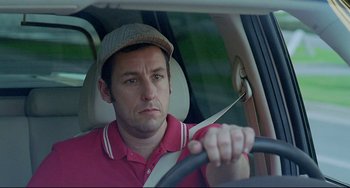 Movie still from “Funny People” (2009), directed by Judd Apatow – A man driving a car in a hat and holding a steering wheel; Close Up shot, Over the shoulder angle