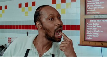 Movie still from “Funny People” (2009), directed by Judd Apatow – A man in a white shirt is taking a bite out of a piece of food; Close Up shot, High angle