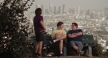 Movie still from “Funny People” (2009), directed by Judd Apatow – A group of people sitting on top of a wooden bench; Wide shot, Over the shoulder angle