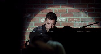 Movie still from “Funny People” (2009), directed by Judd Apatow – A man sitting in front of a laptop computer; Medium shot, Over the shoulder angle
