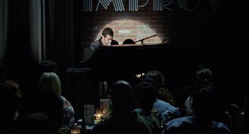 Movie still from “Funny People” (2009), directed by Judd Apatow – A man sitting at a piano in front of a group of diners; Wide shot, High angle