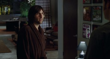 Movie still from “Funny People” (2009), directed by Judd Apatow – A man in a robe standing in front of a living room door; Medium shot, Over the shoulder angle