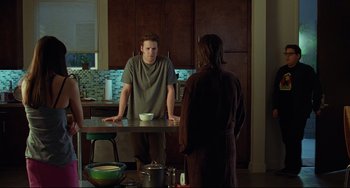 Movie still from “Funny People” (2009), directed by Judd Apatow – A man standing in front of a woman in a kitchen; Medium shot, Over the shoulder angle