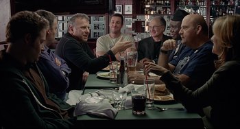 Movie still from “Funny People” (2009), directed by Judd Apatow – A group of people sitting at a table with drinks; Medium shot, Over the shoulder angle