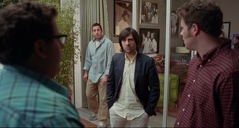 Movie still from “Funny People” (2009), directed by Judd Apatow – A group of men standing next to each other in a room; Wide shot, Over the shoulder angle