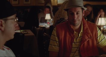 Movie still from “Funny People” (2009), directed by Judd Apatow – A man sitting at a table in front of other people; Medium shot, Over the shoulder angle