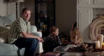 Movie still from “Funny People” (2009), directed by Judd Apatow – A man and two children sitting in a living room; Medium shot, Over the shoulder angle