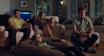 Movie still from “Funny People” (2009), directed by Judd Apatow – A group of people sitting in a living room next to each other; Wide shot, Over the shoulder angle