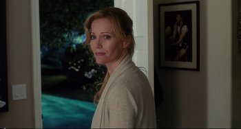 Movie still from “Funny People” (2009), directed by Judd Apatow – A woman standing in front of a wall with a painting behind her; Medium shot, Over the shoulder angle