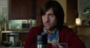 Movie still from “Funny People” (2009), directed by Judd Apatow – A man sitting at a table with a cup in front of him; Close Up shot, Over the shoulder angle