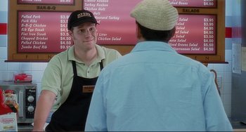 Movie still from “Funny People” (2009), directed by Judd Apatow – A man is talking to another man in front of a sign; Medium shot, Over the shoulder angle