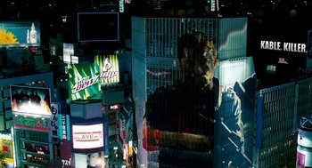 Movie still from “Gamer” (2009), directed by Mark Neveldine – A man standing in front of a building in the middle of a city; Extreme Wide shot, Low angle