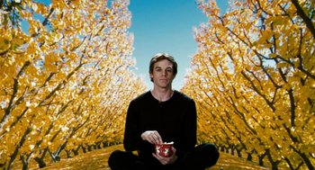Movie still from “Gamer” (2009), directed by Mark Neveldine – A man sitting in the middle of a field holding a bowl; Wide shot, Low angle