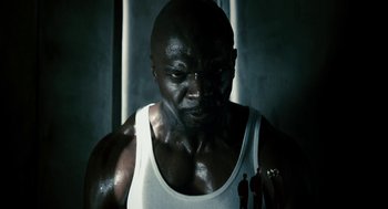 Movie still from “Gamer” (2009), directed by Mark Neveldine – A man in a white tank top is looking at the camera; Close Up shot, Low angle