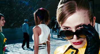 Movie still from “Gamer” (2009), directed by Mark Neveldine – A woman wearing sunglasses and a yellow jacket; Close Up shot, Low angle