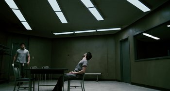 Movie still from “Gamer” (2009), directed by Mark Neveldine – A person sitting on a chair in a room; Wide shot, Low angle