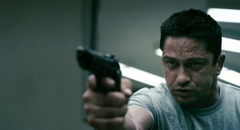 Movie still from “Gamer” (2009), directed by Mark Neveldine – A person holding a gun in a room; Close Up shot, Low angle