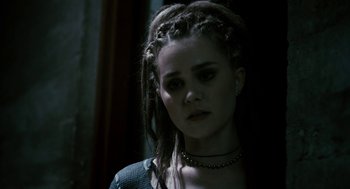 Movie still from “Gamer” (2009), directed by Mark Neveldine – A woman with dreads and a necklace looking at the camera; Close Up shot, Over the shoulder angle