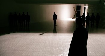 Movie still from “Gamer” (2009), directed by Mark Neveldine – A man standing in a room with a light shining on him; Extreme Wide shot, High angle