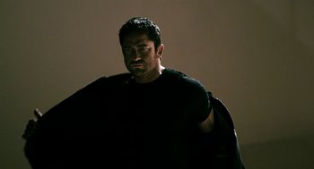 Movie still from “Gamer” (2009), directed by Mark Neveldine – A man in a black shirt is holding something; Medium shot, Low angle