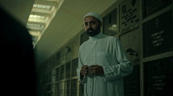 Movie still from “Ganglands” (2021), created by Julien Leclercq – A man standing in a jail cell holding a cell phone; Medium shot, Low angle