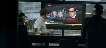 Movie still from “Black Mirror” (2011), created by Charlie Brooker – A man sitting in front of a television; Medium shot, Over the shoulder angle