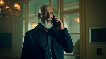 Movie still from “Ganglands” (2021), created by Julien Leclercq – An older man talking on a cell phone; Medium shot, Low angle