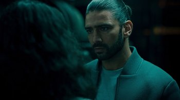 Movie still from “Ganglands” (2021), created by Julien Leclercq – A man with long hair and a beard looking at the camera; Close Up shot, Over the shoulder angle