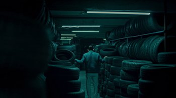 Two men are standing in a room full of tires