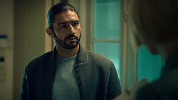 Movie still from “Ganglands” (2021), created by Julien Leclercq – A person wearing a jacket; Close Up shot, Over the shoulder angle