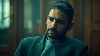 Movie still from “Ganglands” (2021), created by Julien Leclercq – A person wearing a jacket; Close Up shot, Over the shoulder angle