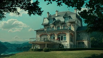 Movie still from “Ganglands” (2021), created by Julien Leclercq – A large house with a balcony on top of it; Extreme Wide shot, Low angle