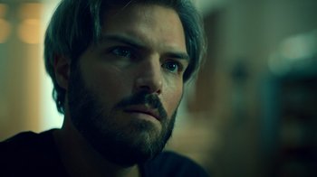 Movie still from “Ganglands” (2021), created by Julien Leclercq – A person with a beard; Close Up shot, Over the shoulder angle